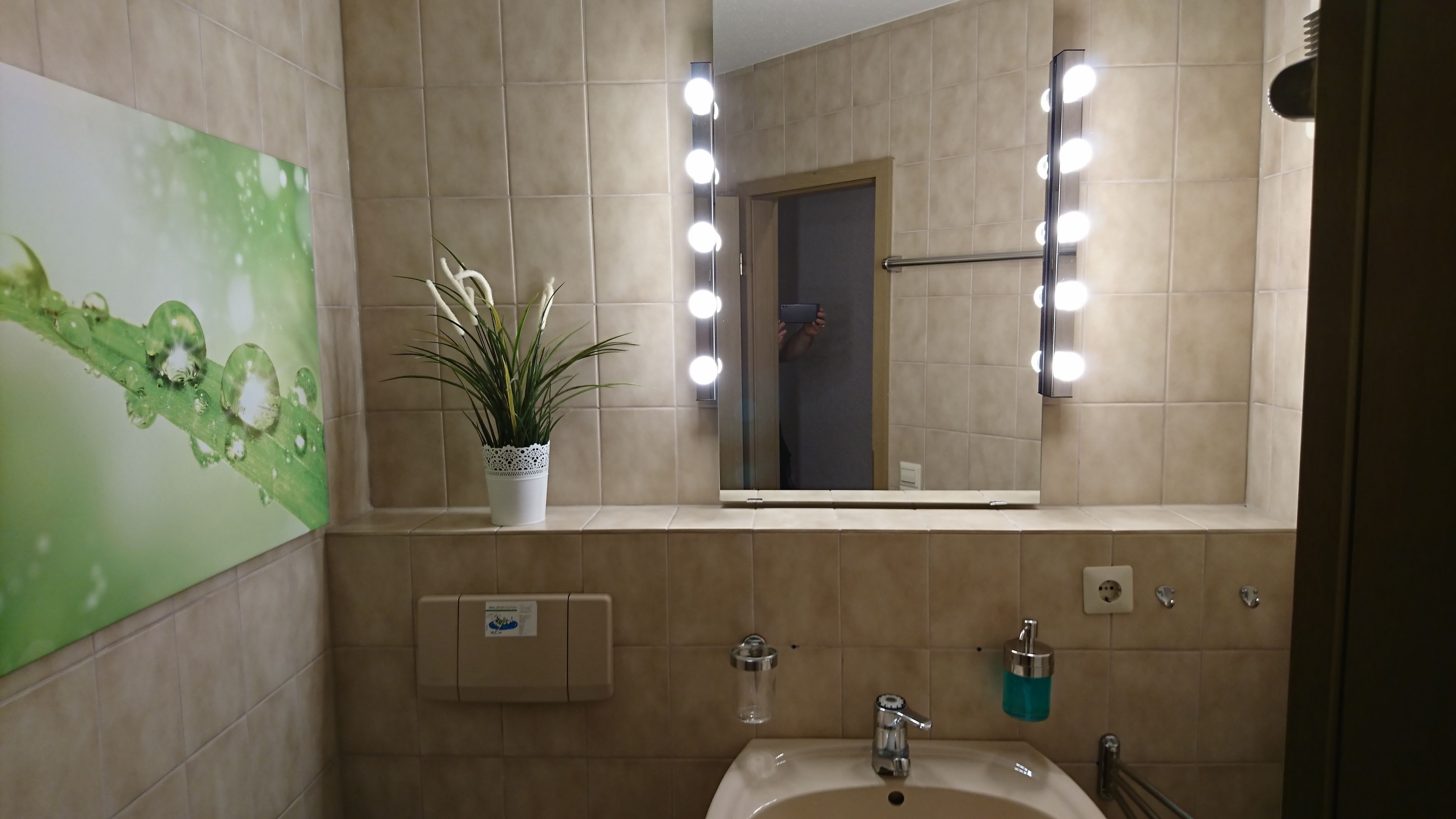 A bathroom with a sink, mirror, and lights.