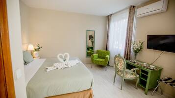 Habitación de hotel con cama, escritorio, silla, televisor y aire acondicionado.