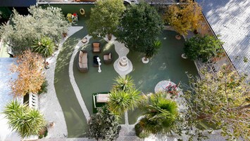 Vista aérea de un patio con una fuente, zonas de estar y diversos árboles.