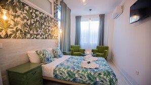 Habitación de hotel con una cama, una mesita de noche verde, una silla verde y un televisor en la pared.