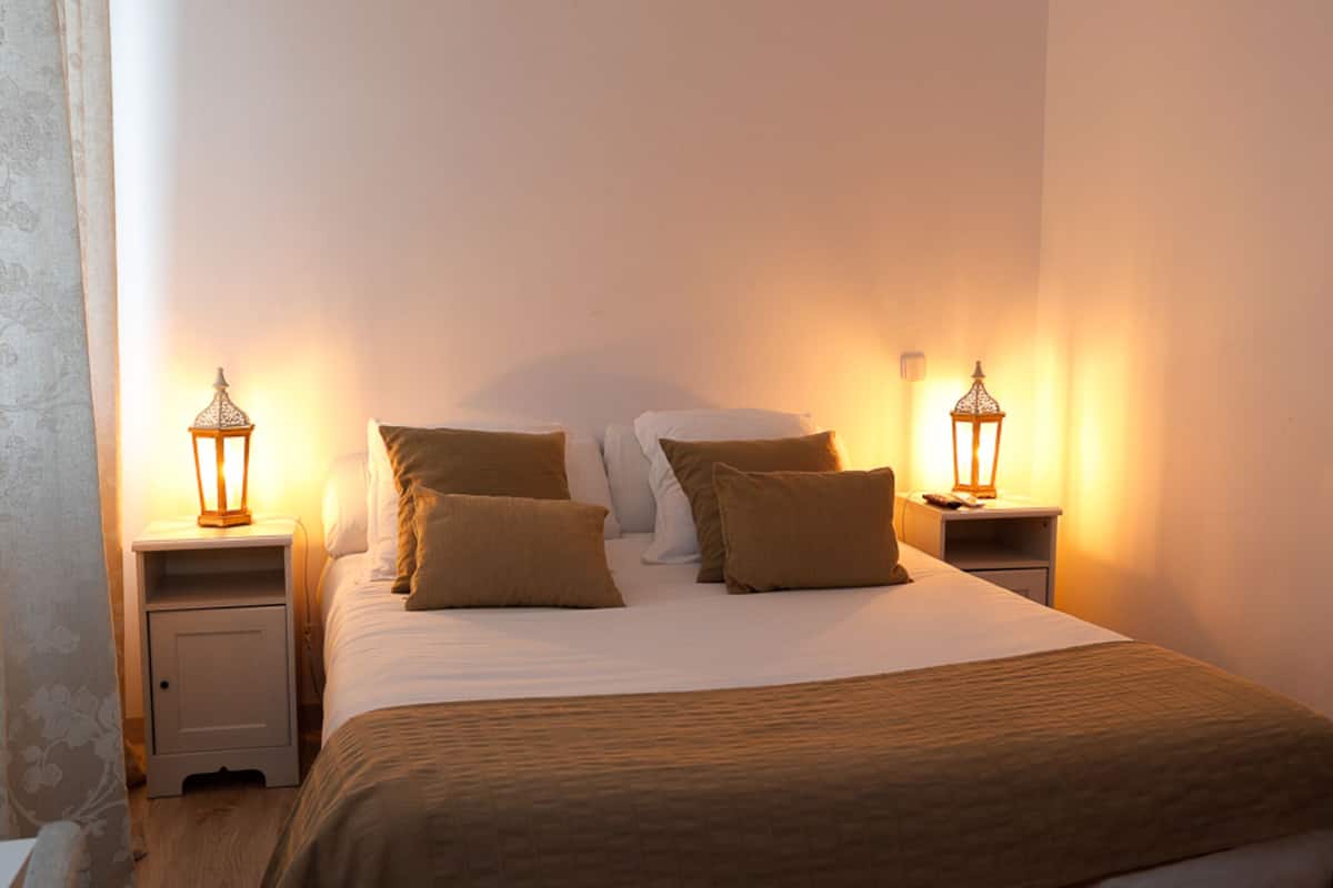 A neatly made bed with a brown bedspread and pillows, flanked by two bedside tables with lantern-style lamps.