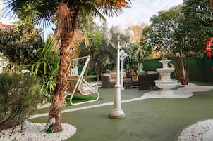 A garden area with a swing chair, a white lamp post, and a fountain.