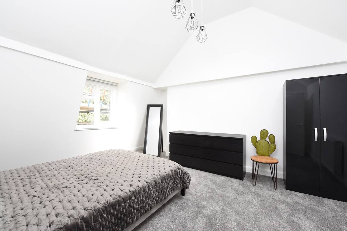 Un dormitorio con cama, cómoda, silla, armario y ventana.