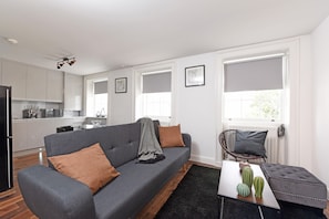A modern living room with a grey sofa, a coffee table, and a black rug. - Charming & Modern Apartments near Oxford Circus London (London)