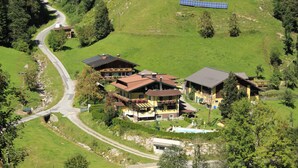 A hillside property with multiple buildings, a winding road, and solar panels. - Schattaugut (Eben im Pongau)