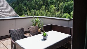 A balcony with wicker furniture, a table, and a potted plant. - Schattaugut (Eben im Pongau)