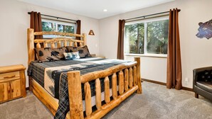 A bedroom with a wooden bed, a window with curtains, a small wooden cabinet, and a leather sofa.