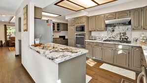 A modern kitchen with a large island, built-in appliances, and a marble backsplash.
