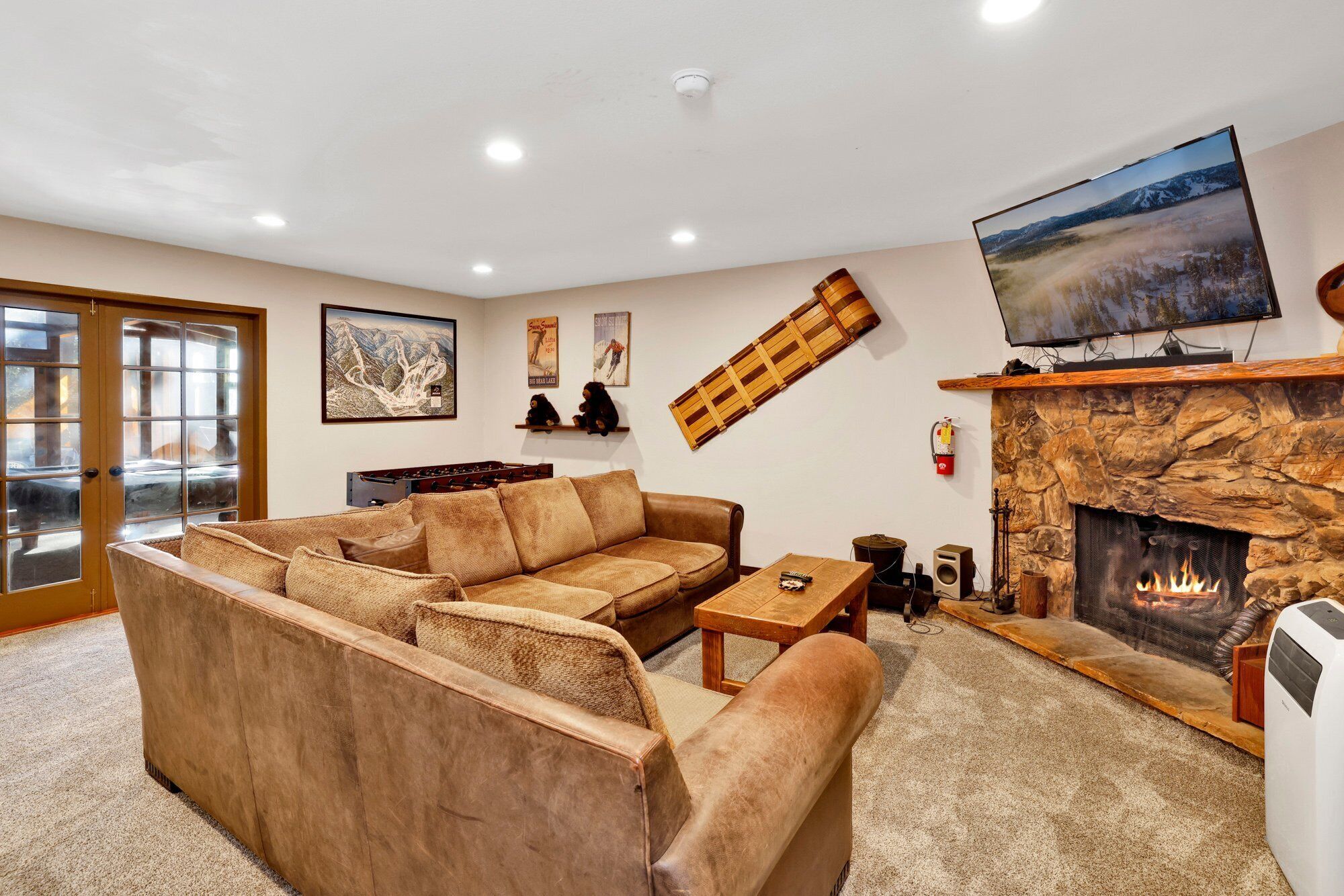 A cozy living room with a sectional sofa, a fireplace, a mounted TV, and a stone wall.