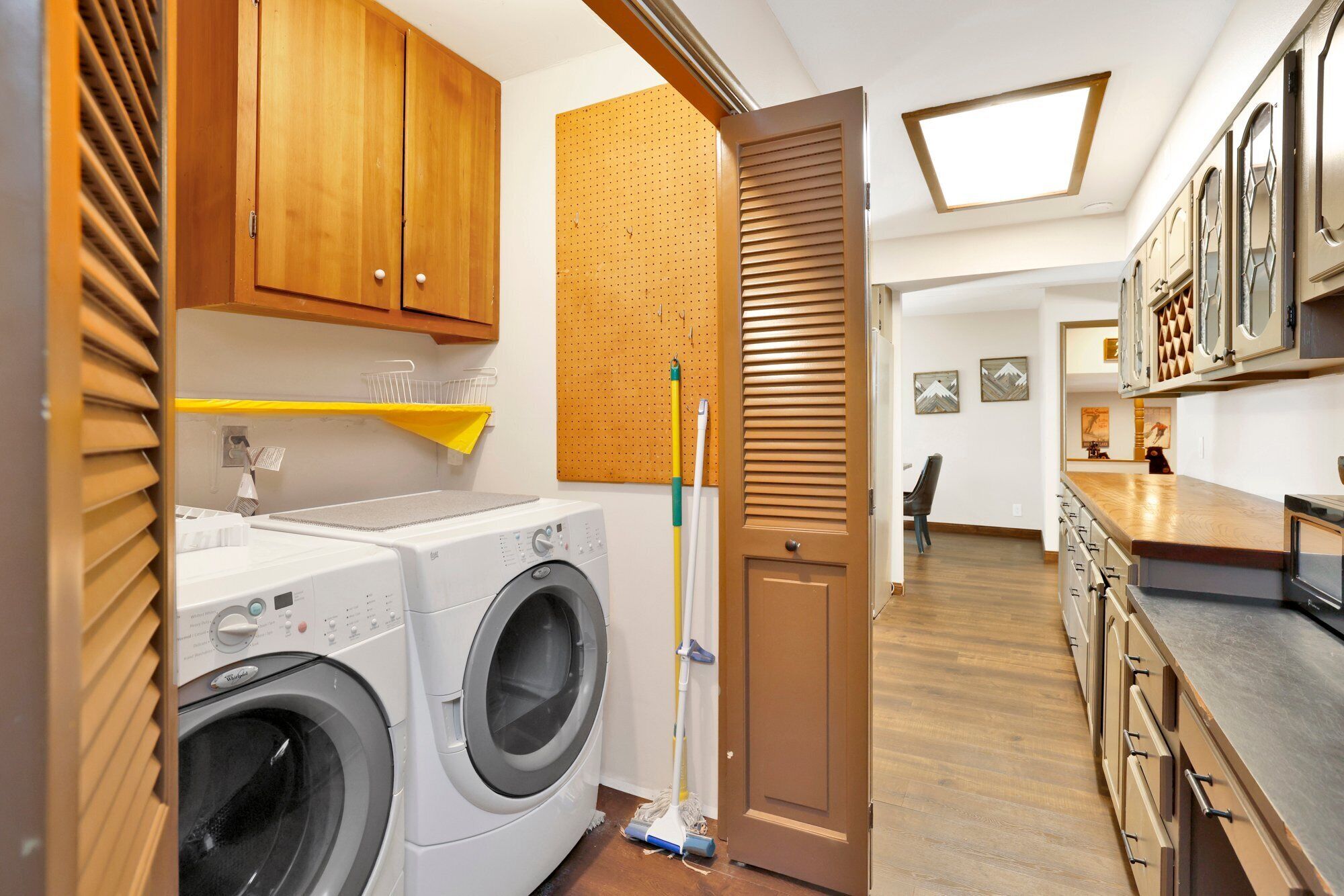 Un espace dédié à la lessive, comprenant un lave-linge, une serpillière et des armoires en bois.
