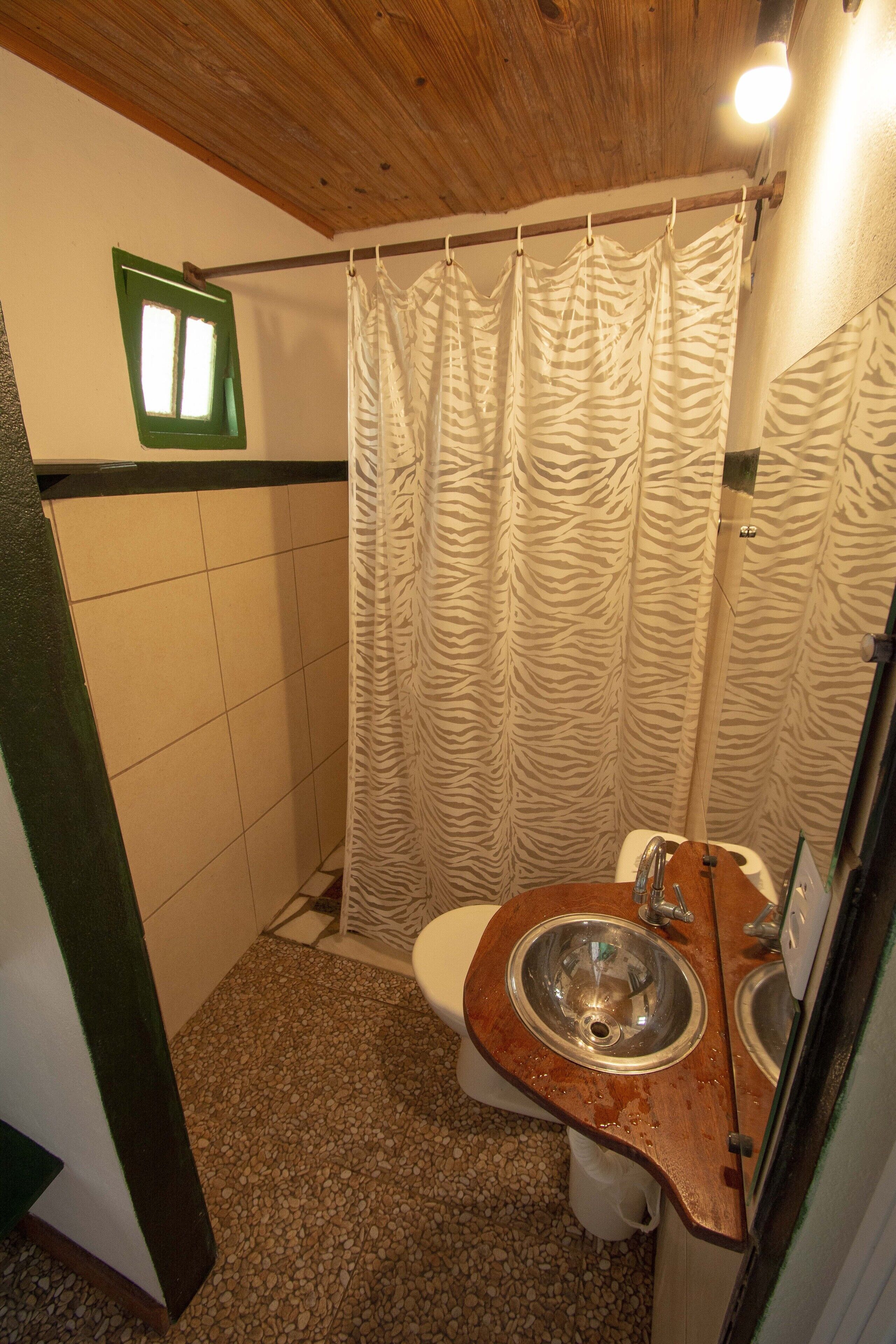 A small bathroom with a wooden vanity, two sinks, a toilet, and a zebra-patterned shower curtain.