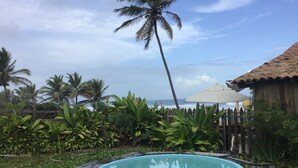 A pool surrounded by tropical vegetation and a wooden structure with a tiled roof. - Casa ImBale (Mata de São João)
