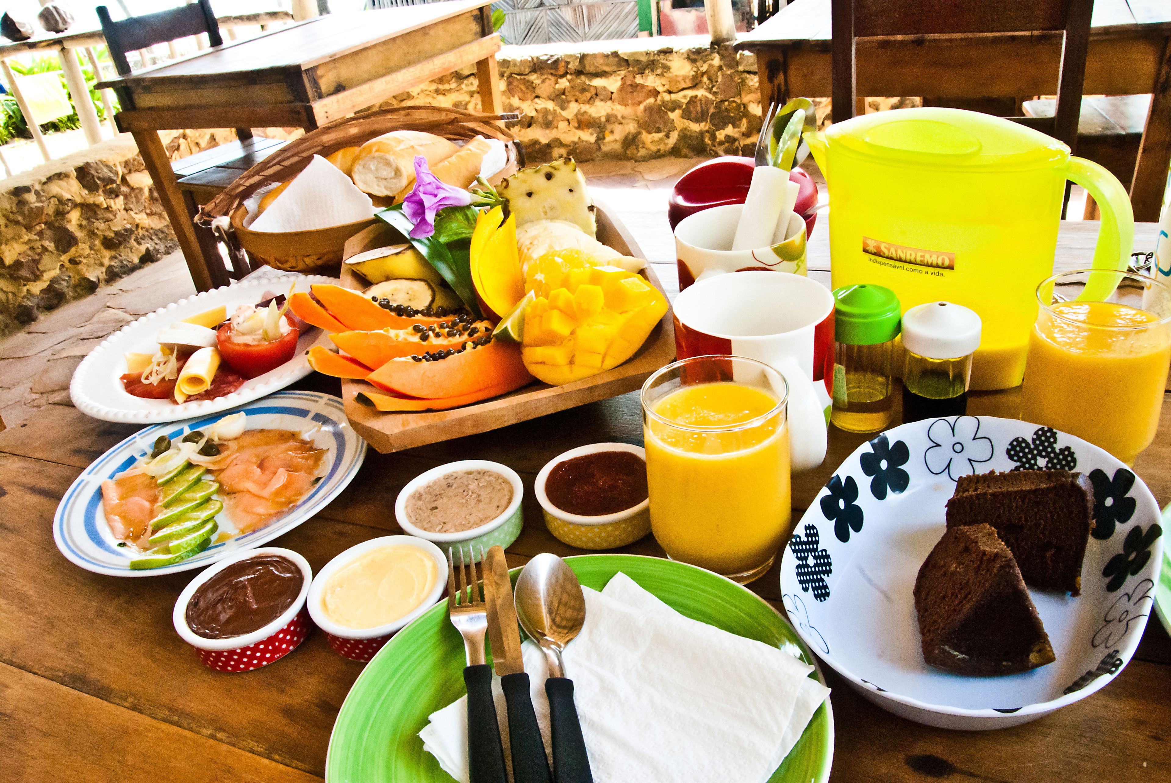 Una mesa dispuesta con una variedad de alimentos para el desayuno, incluyendo frutas, pasteles y bebidas.