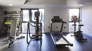 Un gimnasio con cintas de correr, elípticas y un soporte para pesas.