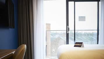A hotel room with a bed, a desk, and a chair.