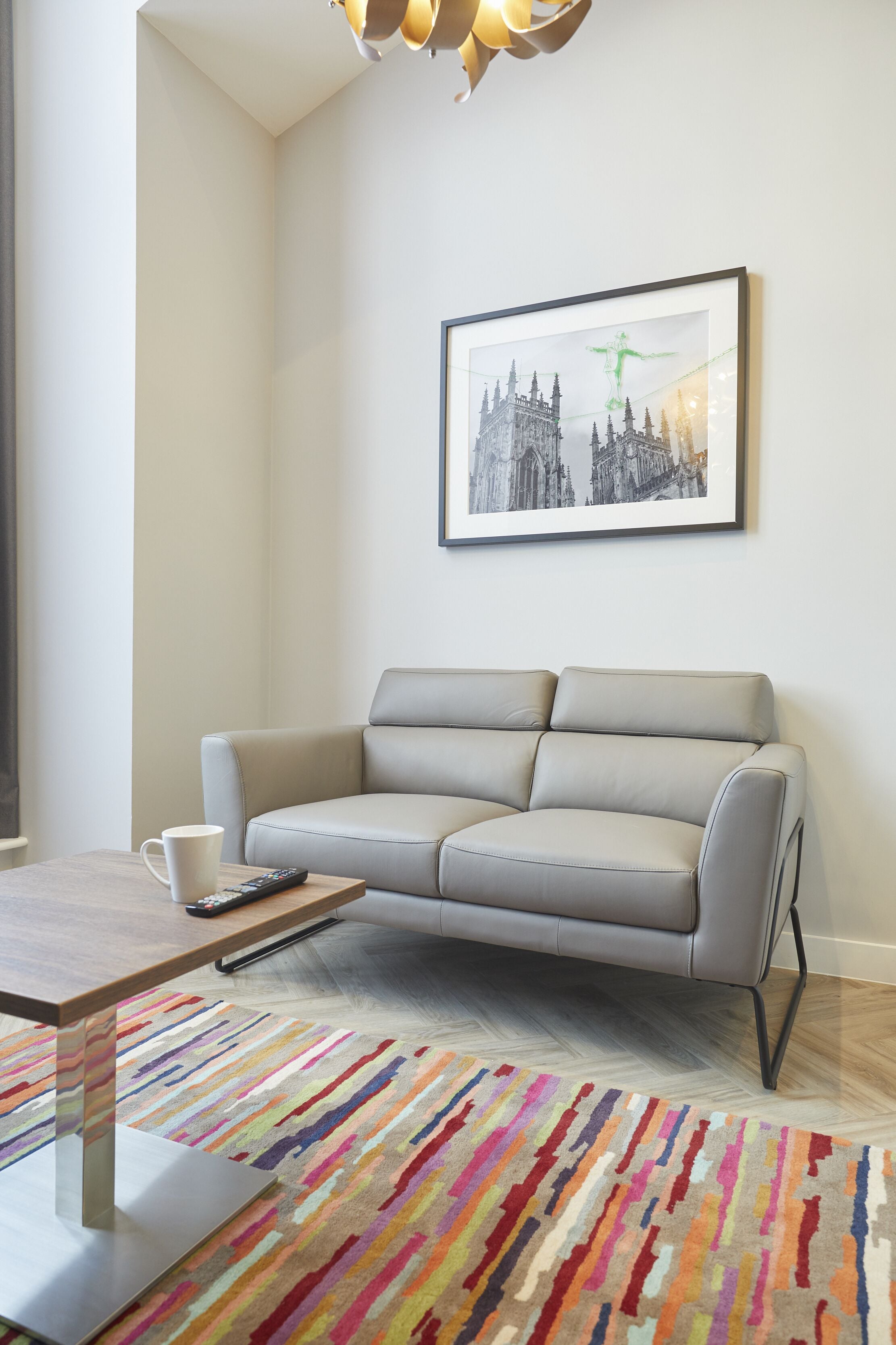 A modern living room with a grey sofa, a coffee table, and a colorful striped rug.