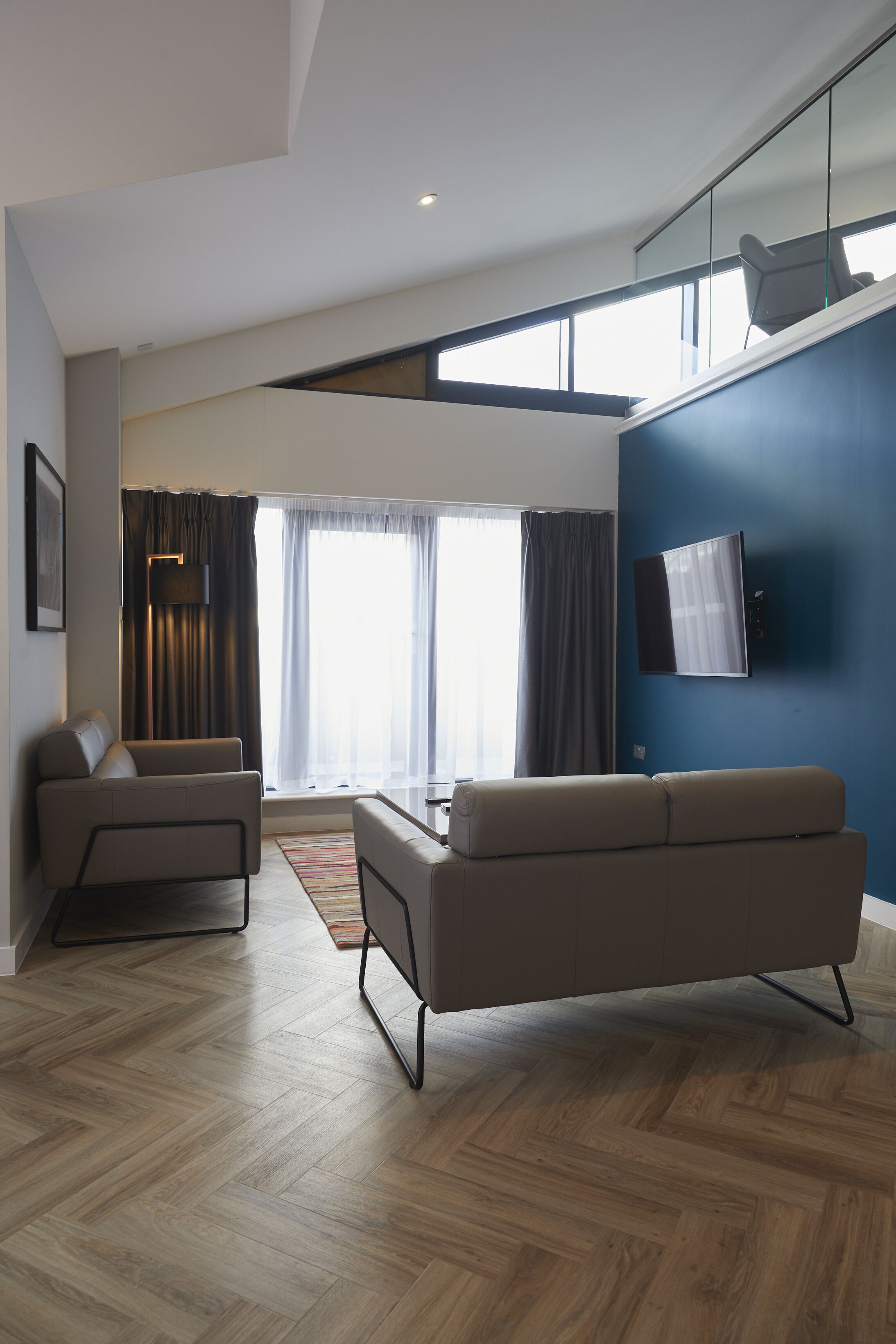 A modern living room with a sofa, a coffee table, and a TV mounted on a blue wall.