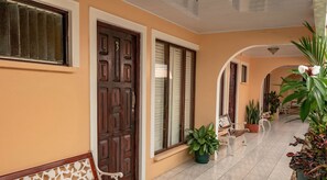 Un pasillo con suelo de baldosas, puertas de madera y plantas en macetas.