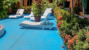 A hotel named 'Cabinas El Coral' with a pool area featuring lounge chairs and potted plants. - Hotel y Cabinas El Coral (Jacó)