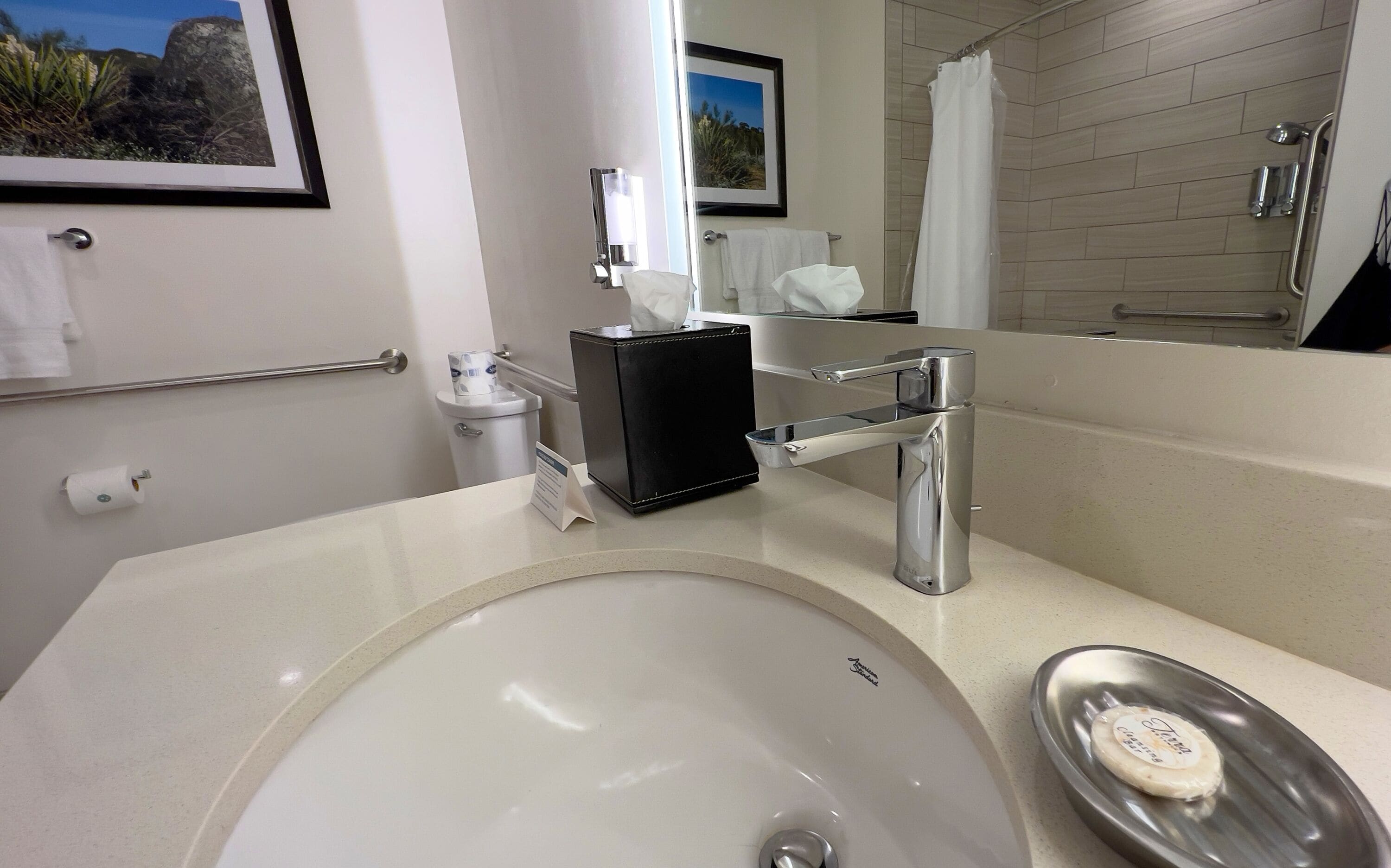 Un baño moderno con un lavamanos grande, un espejo, un inodoro y una zona de ducha.