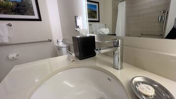 Un baño moderno con un lavamanos grande, un espejo, un inodoro y una zona de ducha.