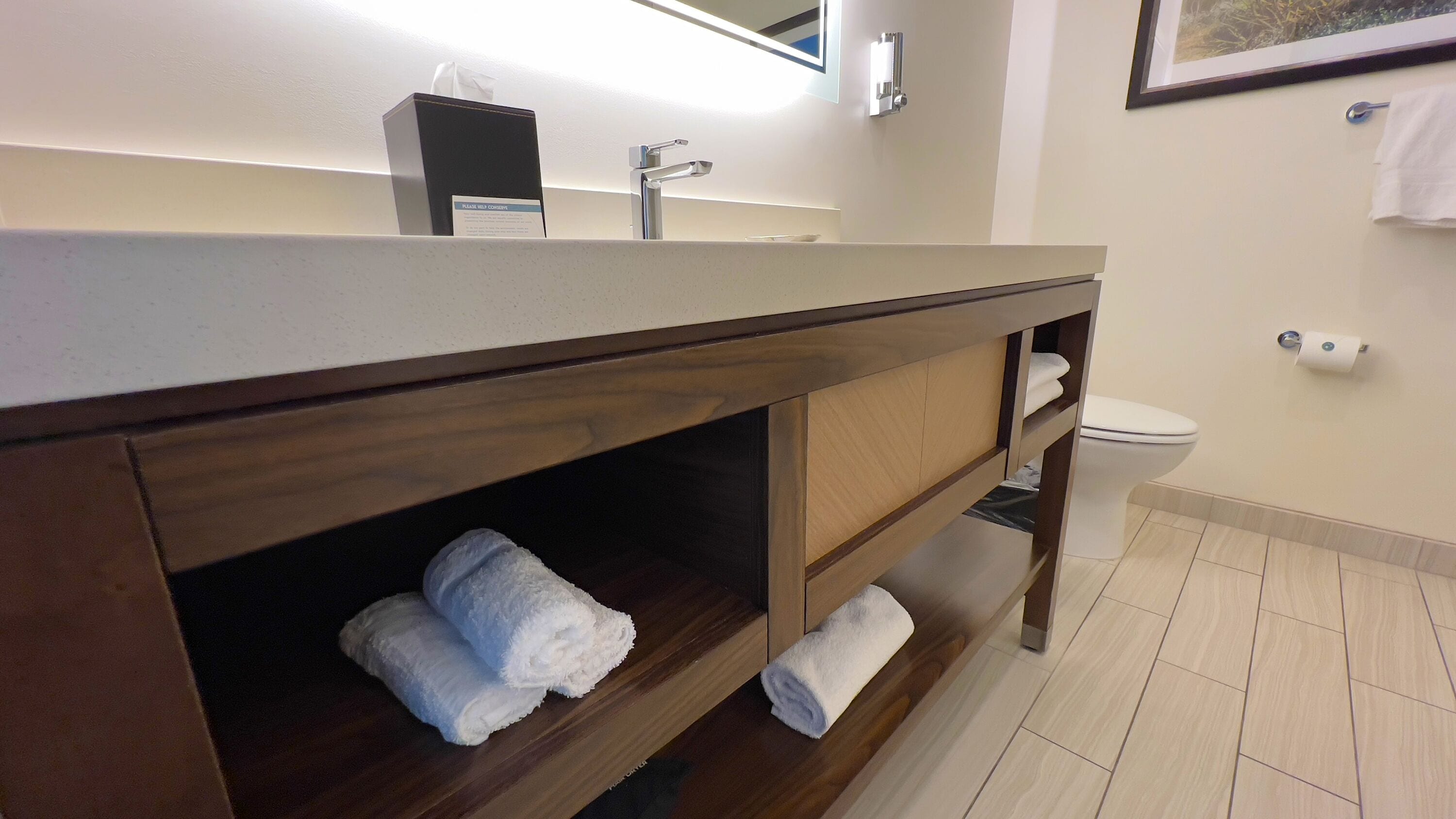 A modern bathroom with a wooden vanity, a sink, and a toilet.