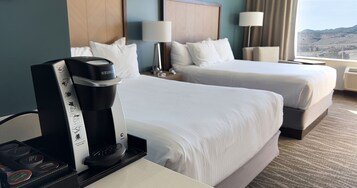 Ein Hotelzimmer mit zwei Betten, einer Keurig-Kaffeemaschine und Blick auf eine gebirgige Landschaft.