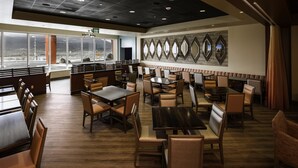 A restaurant with booths and tables, large windows, and a view of the outdoors.