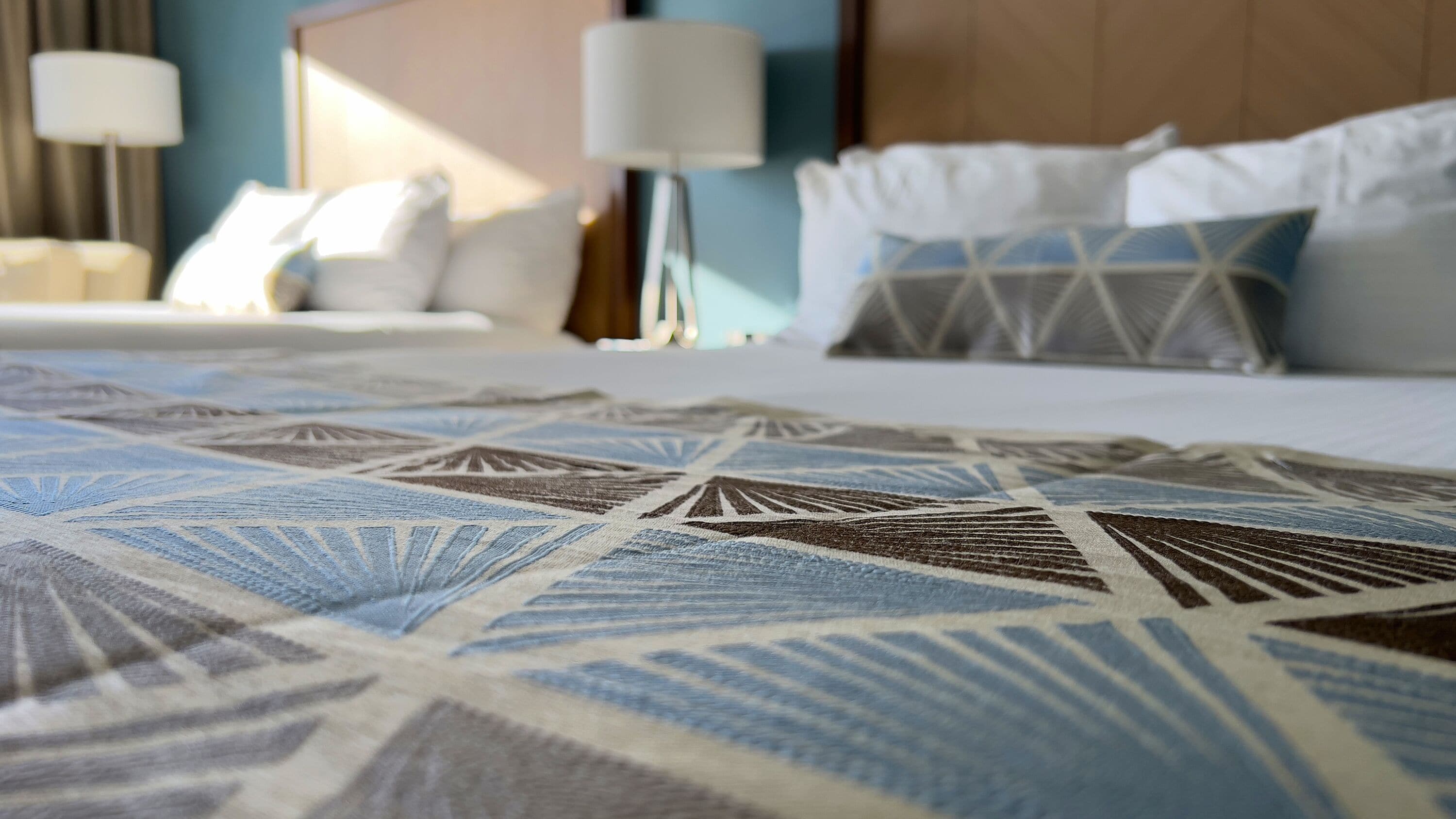 Una habitación de hotel con una cama bien hecha, una colcha estampada y un cabecero.