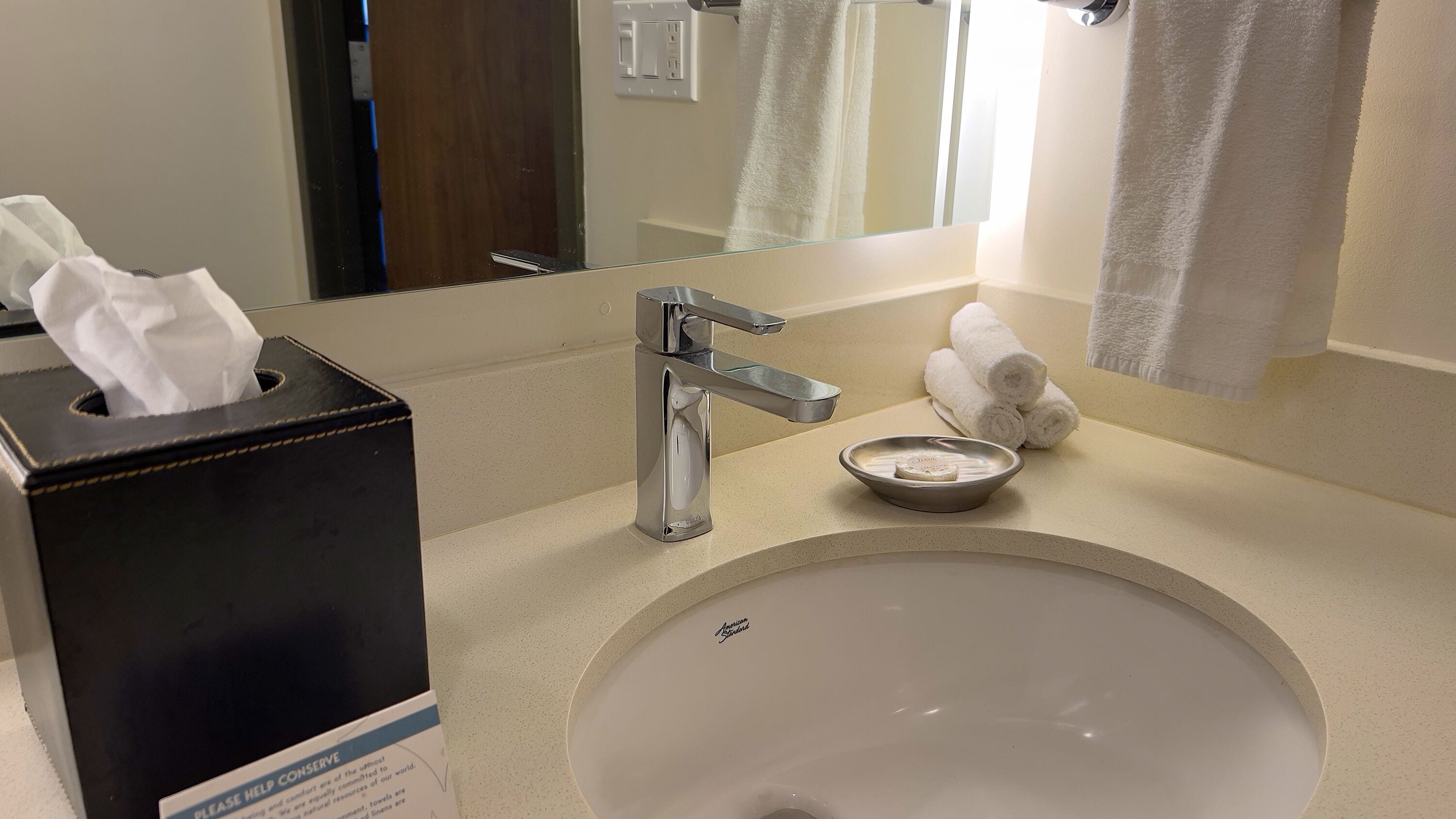 A hotel bathroom with a sink, a tissue box, a soap dish, and towels.