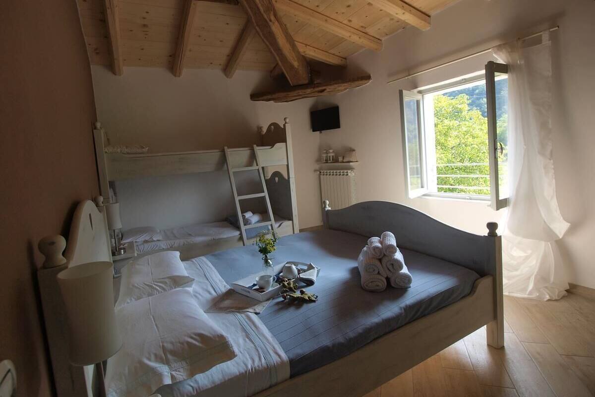 A bedroom with a bed, bedside table, lamp, and a window with curtains.