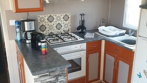 Cocina compacta con estufa a gas, horno, cafetera y lavabo.