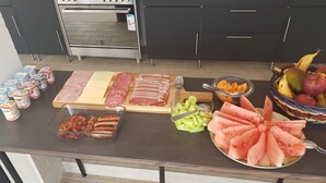 Una mesa de buffet con diversos alimentos, como carnes, quesos, frutas y verduras.