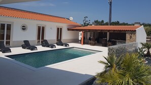 Una casa moderna con piscina, mobiliario de exterior y antena parabólica.