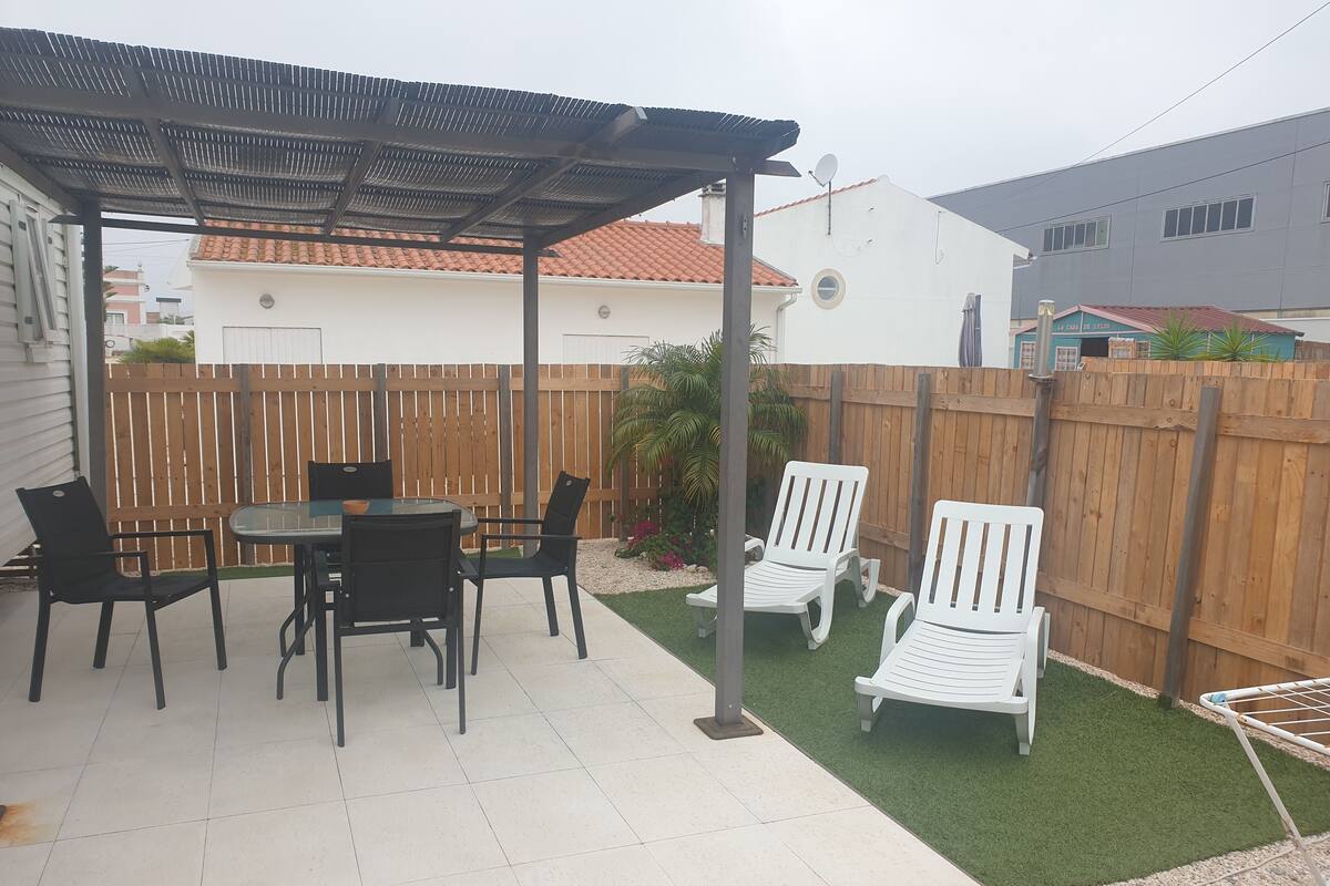 Une terrasse avec une table et des chaises, une pergola et une clôture en bois.