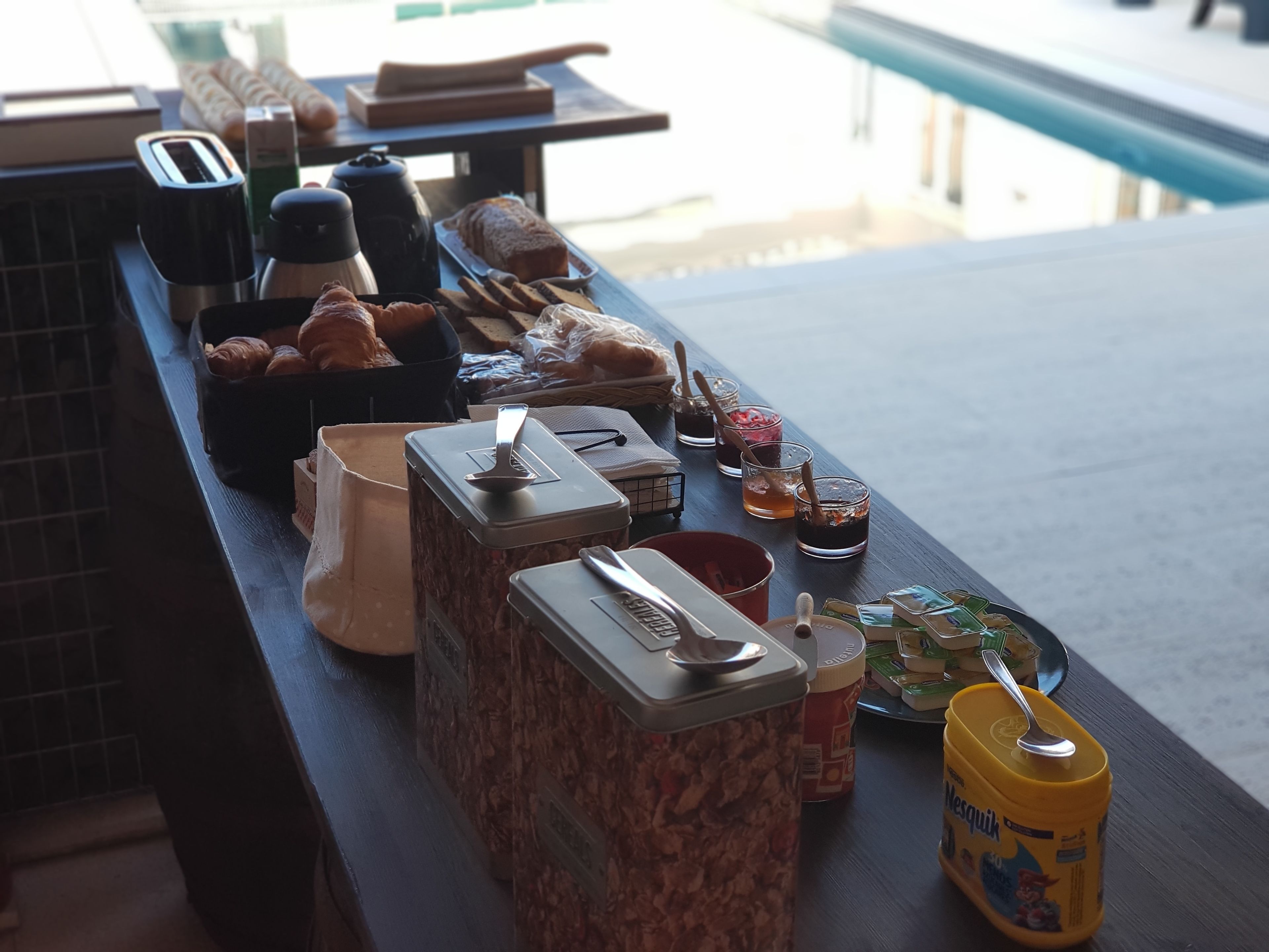 Una barra de desayuno con diferentes alimentos, como bollería, pan y salsas.