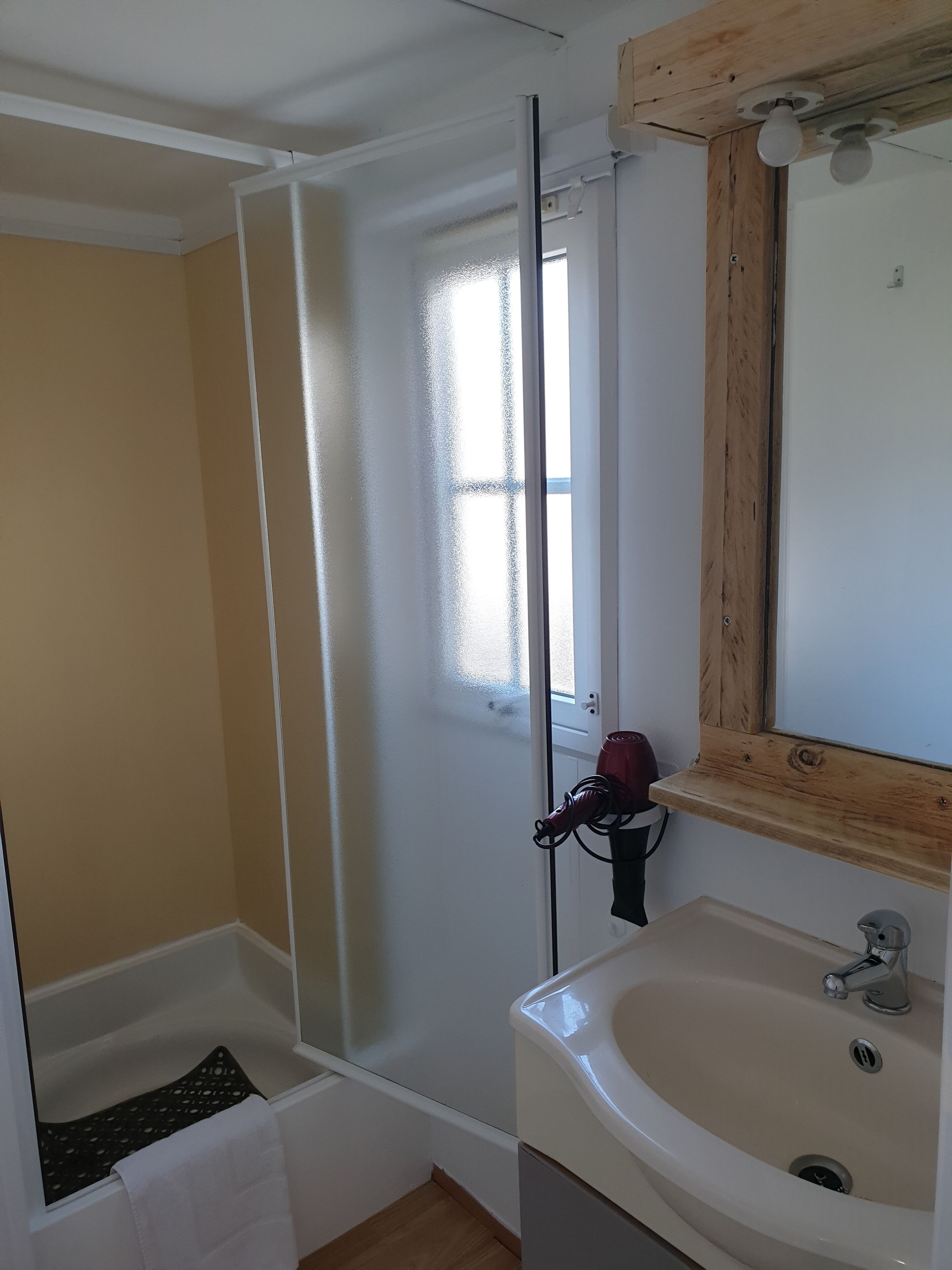A bathroom with a bathtub, a sink, and a window.
