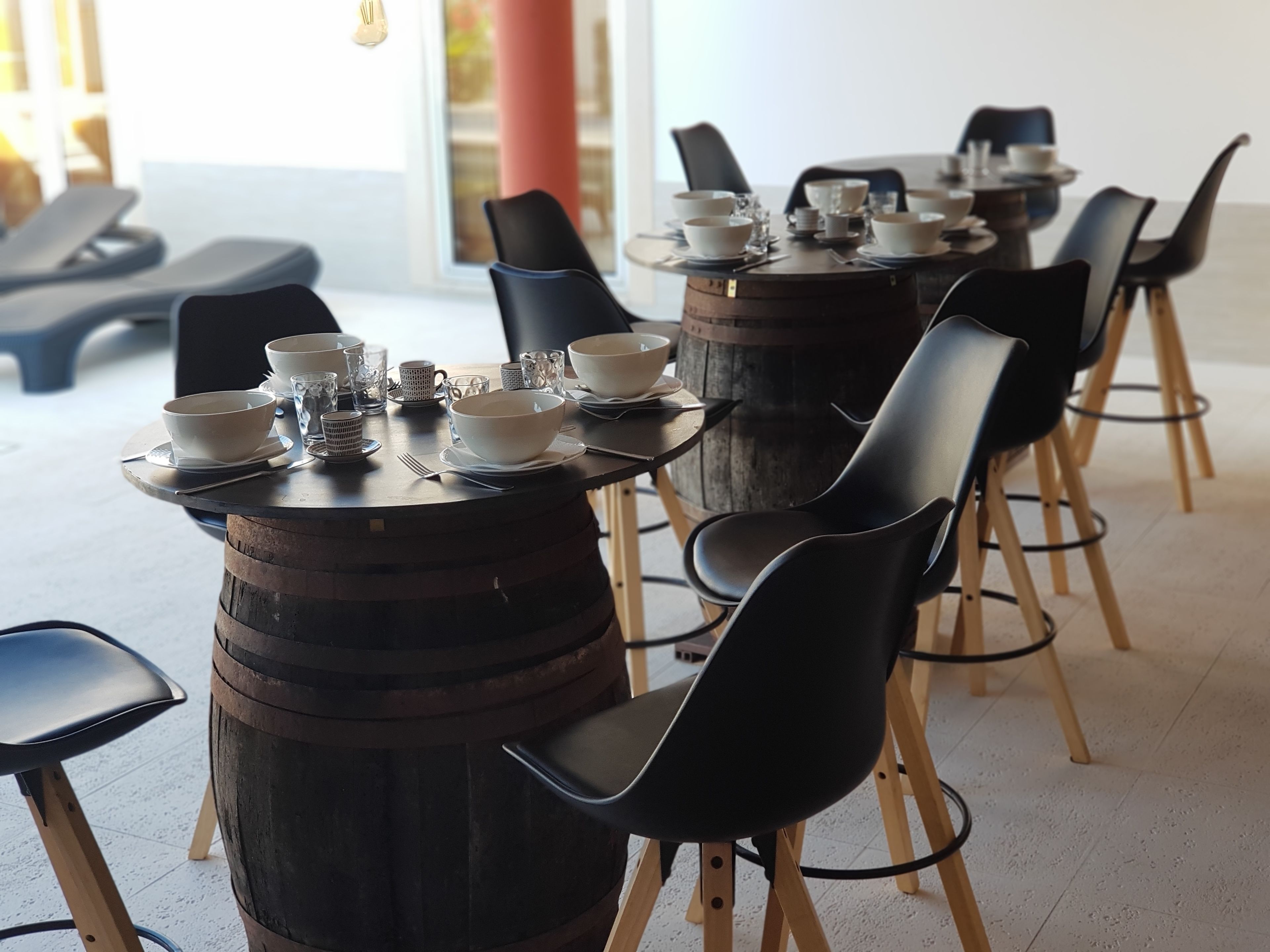 A dining area with round tables and black chairs, each with a wooden barrel base.