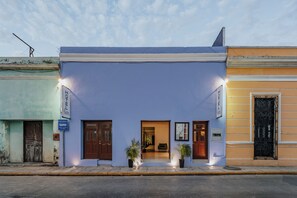 A hotel facade with a blue exterior, a welcoming entrance, and a sign indicating it is an exclusive hotel.