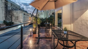An outdoor patio with a table and chairs, a large umbrella, and potted plants. - Hotel Casa Nova Mérida (Mérida)