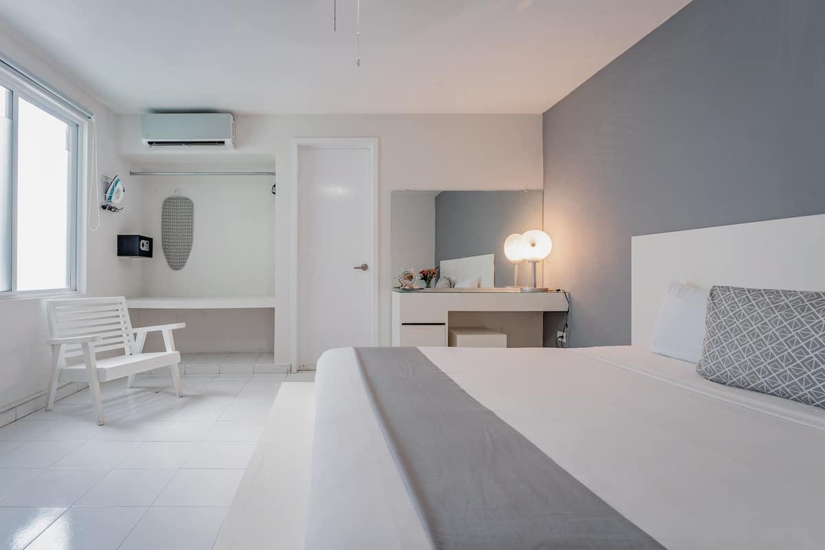 A modern bedroom with a bed, bedside table, lamp, and a desk with a chair.