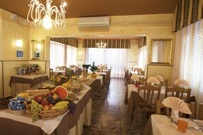 A hotel dining area with tables set for breakfast, featuring a variety of fruits and pastries. - Hotel Villa Bruna (Caorle)