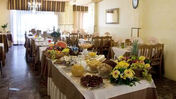 A dining area with multiple tables set for a meal, featuring a variety of food items and a clock on the wall.