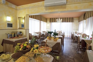 Comedor con mesas dispuestas para una comida, un frutero y una jarra de jugo.
