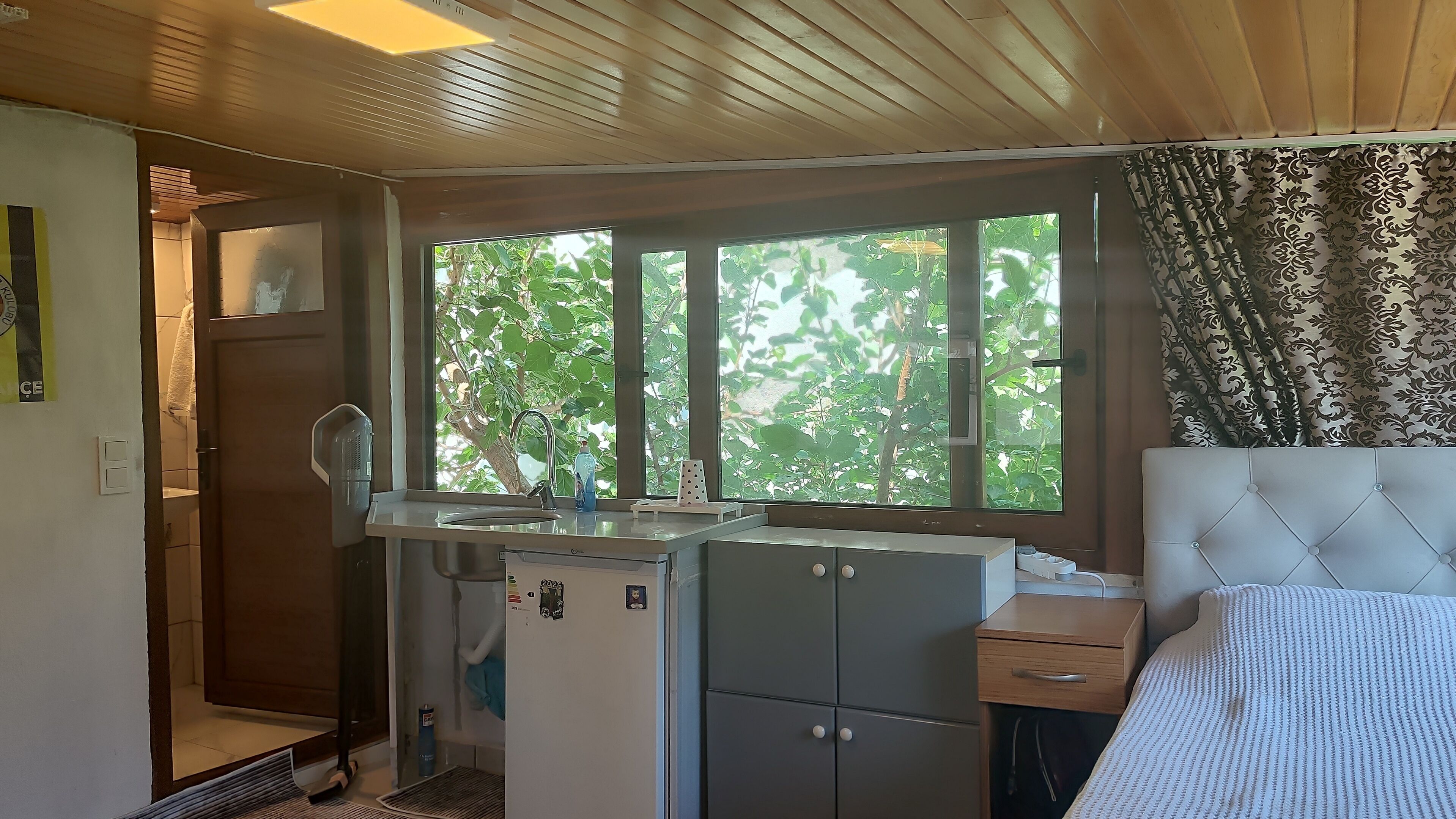 Habitación compacta con kitchenette, una cama y ventana con vista a zonas verdes.