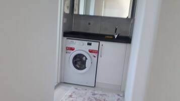 Une buanderie équipée d’un lave-linge, d’un évier et d’un plan de travail.