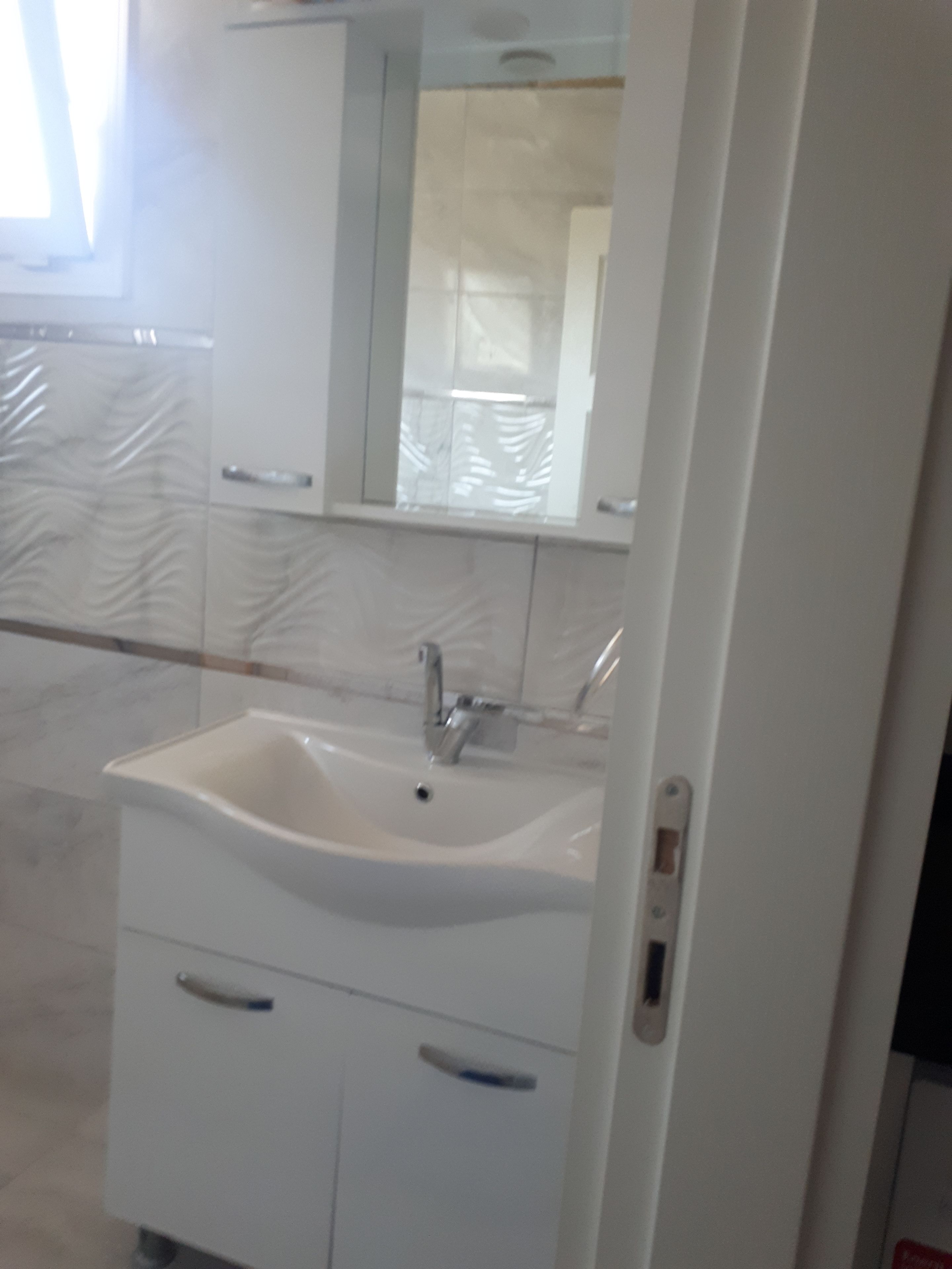 Ein Badezimmer mit Waschbecken, Spiegel und Schränken.