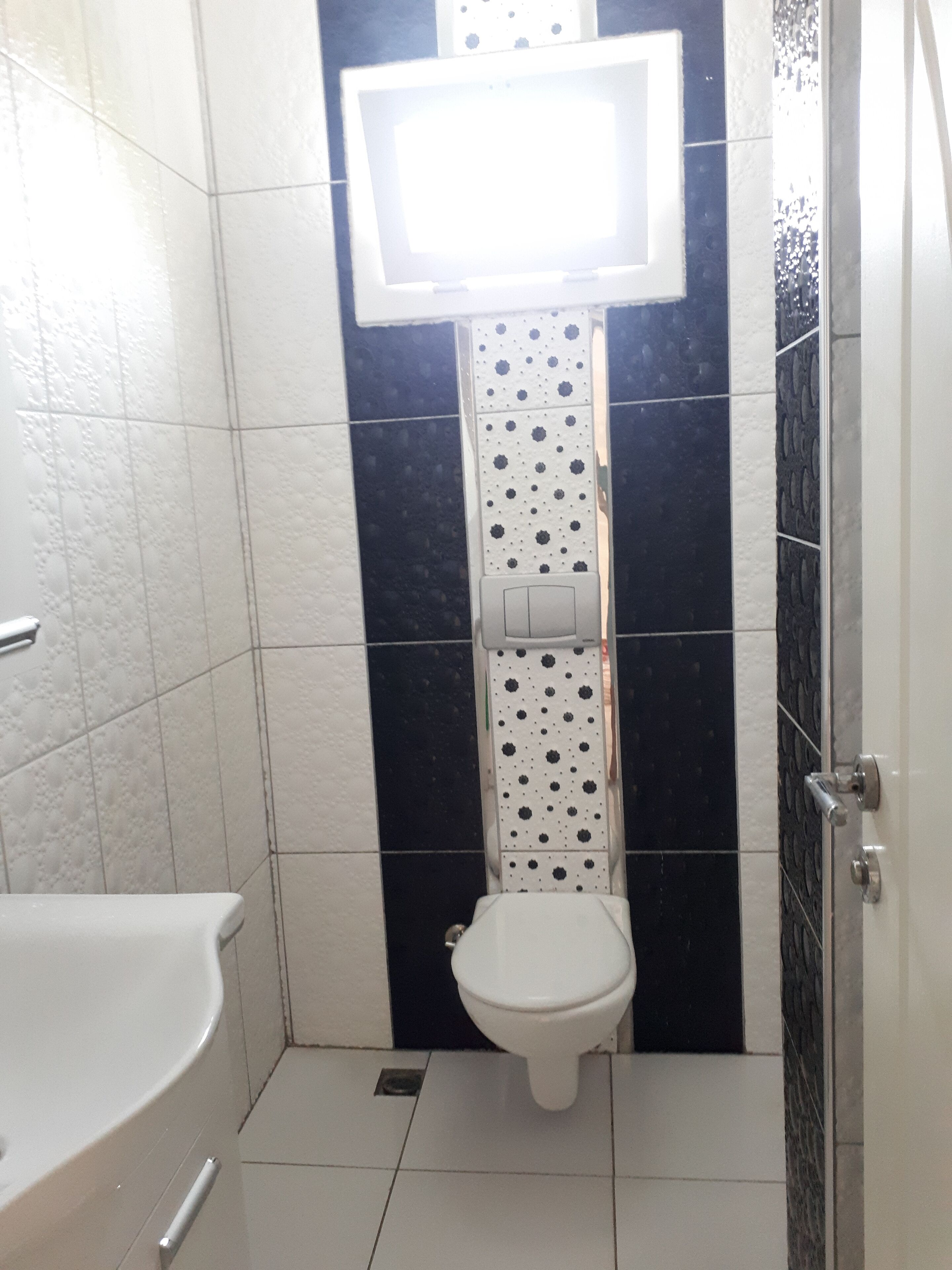 A small bathroom with a toilet, a sink, and a mirror.
