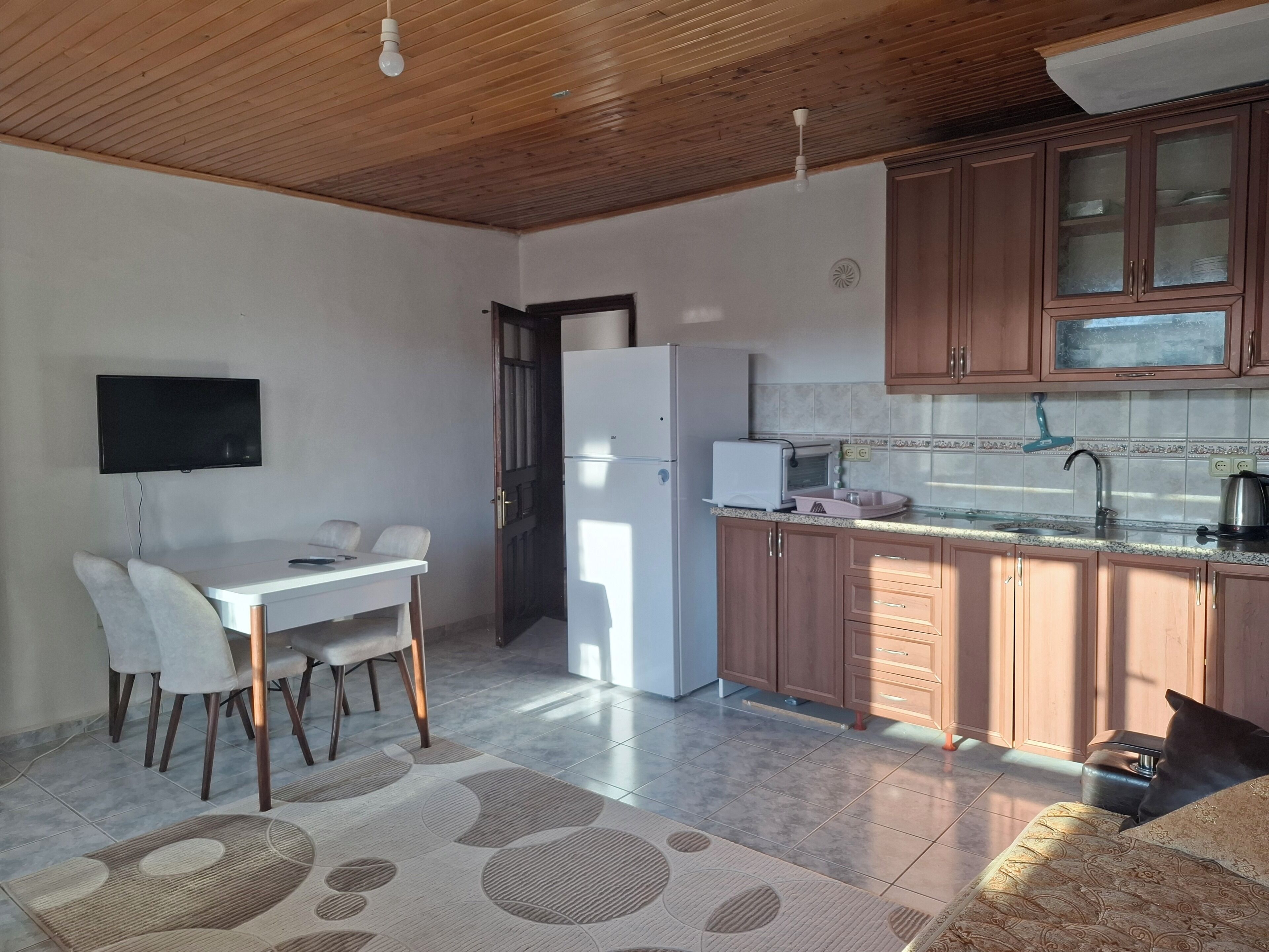 A compact living space with a dining area, kitchenette, and a sofa.