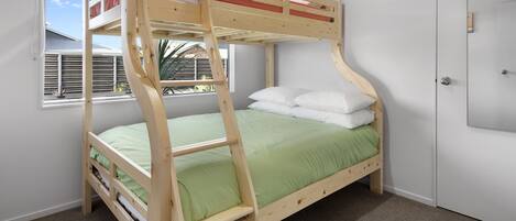 Ein Stockbett mit einer grünen Matratze, weißen Kissen und einem Holzrahmen.